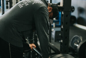 a man leaning over a barbell and recovering between sets
